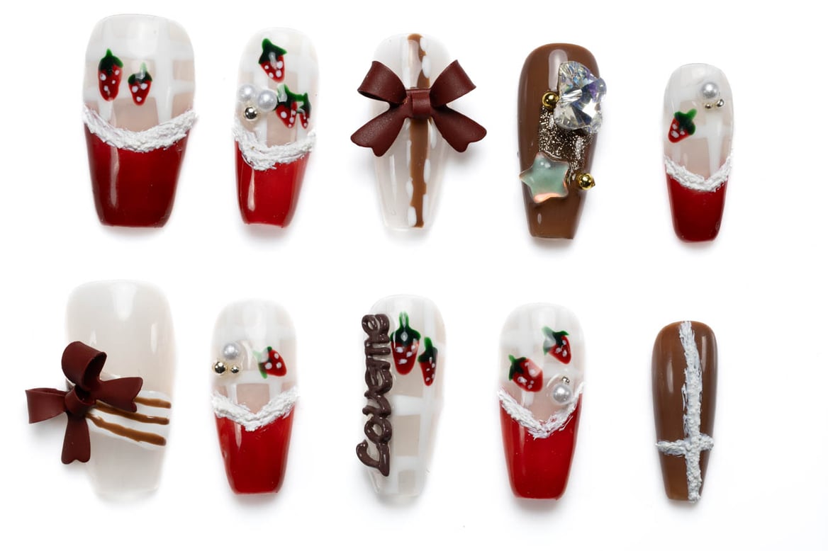 Festive coffin press-on nails with Christmas design featuring strawberries, bows, and holiday embellishments in red, white, and brown