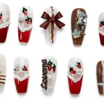 Festive coffin press-on nails with Christmas design featuring strawberries, bows, and holiday embellishments in red, white, and brown