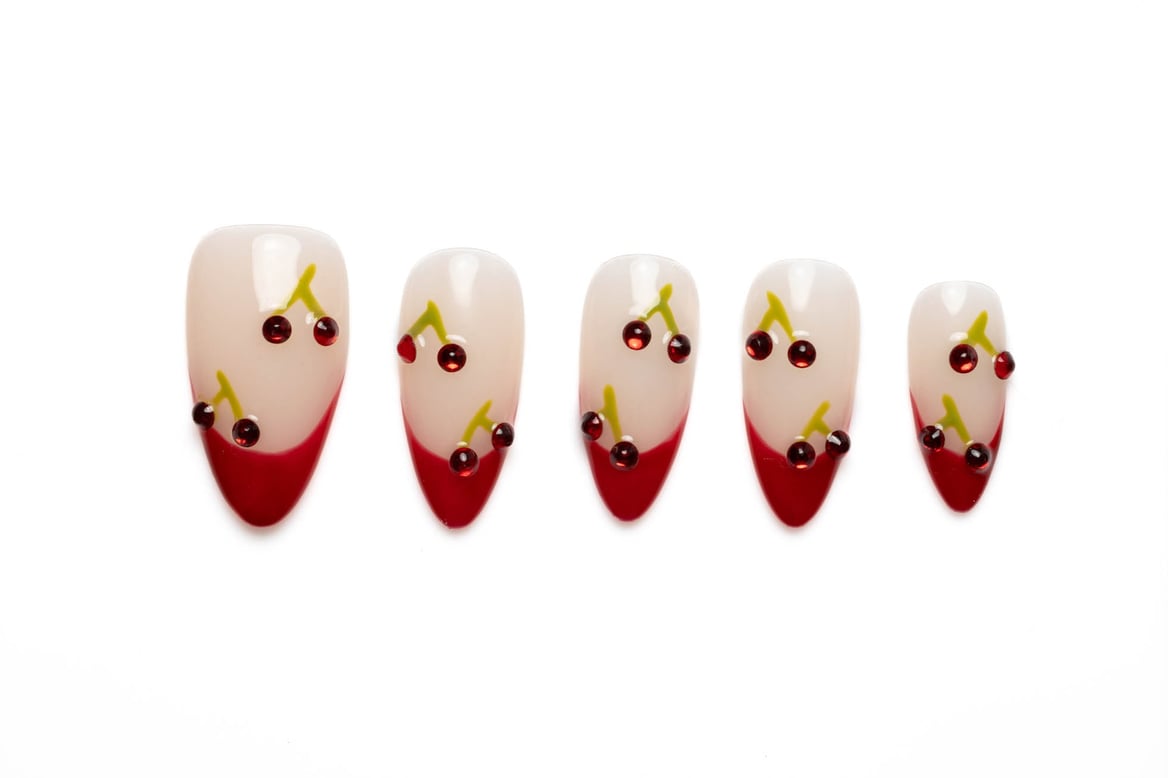 Almond-shaped press-on nails with a cherry French tip design and 3D cherry accents