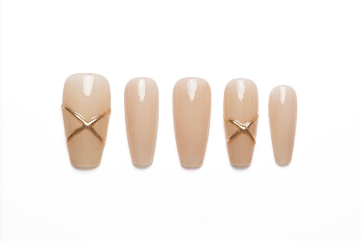 Long nude coffin press-on nails with minimalist gold X accent design and glossy finish