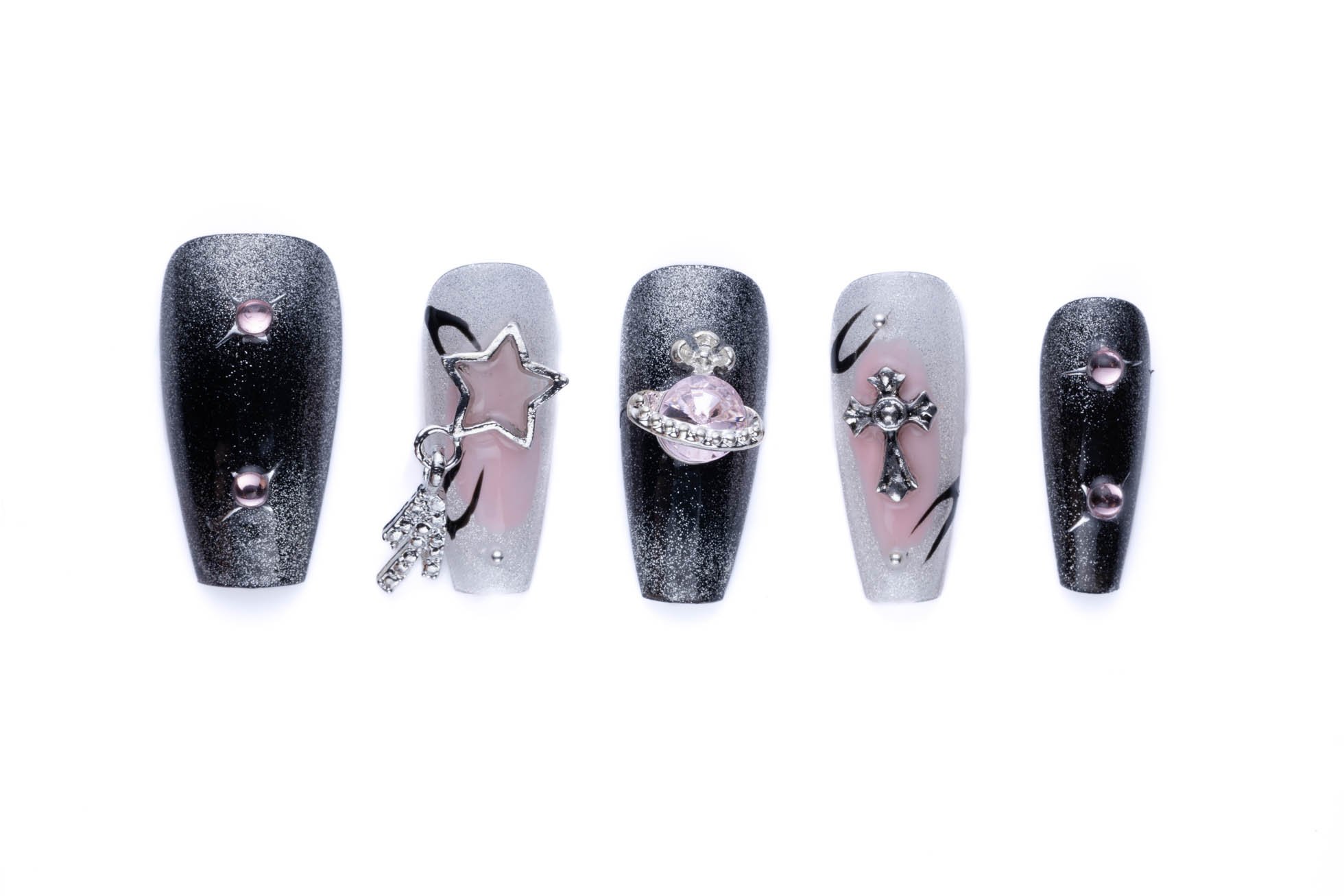 Edgy coffin-shaped press-on nails with black and sheer finishes, decorated with celestial charms like stars, orbs, and crosses.