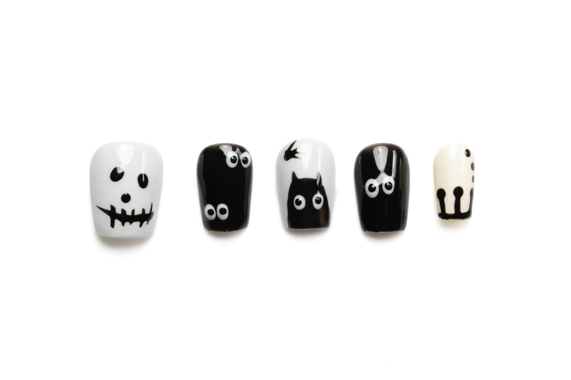 Short squoval Halloween press-on nails featuring black and white spooky designs with ghost faces, googly eyes, and black cats