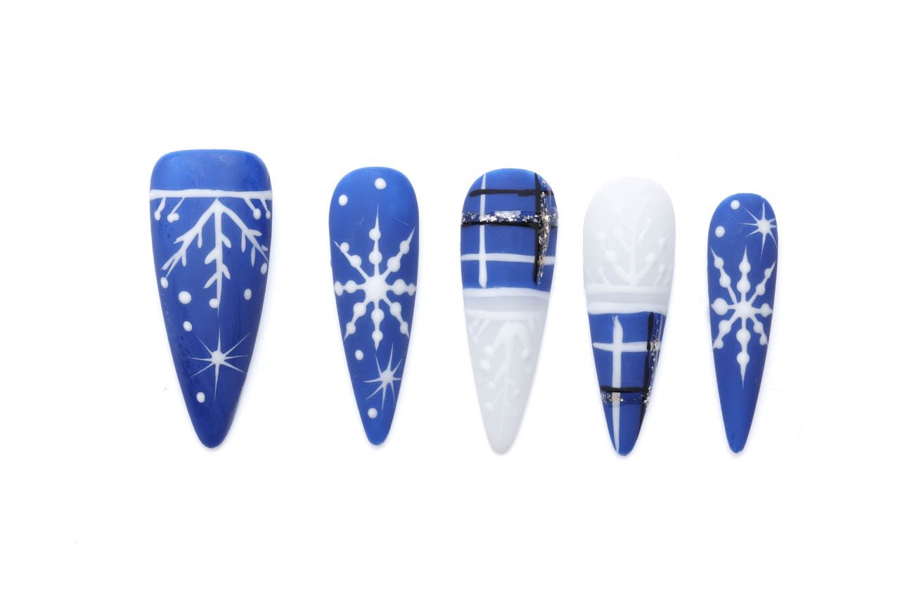 Winter snowflake press-on nails in blue and white with almond shape and silver accents, perfect for holiday season