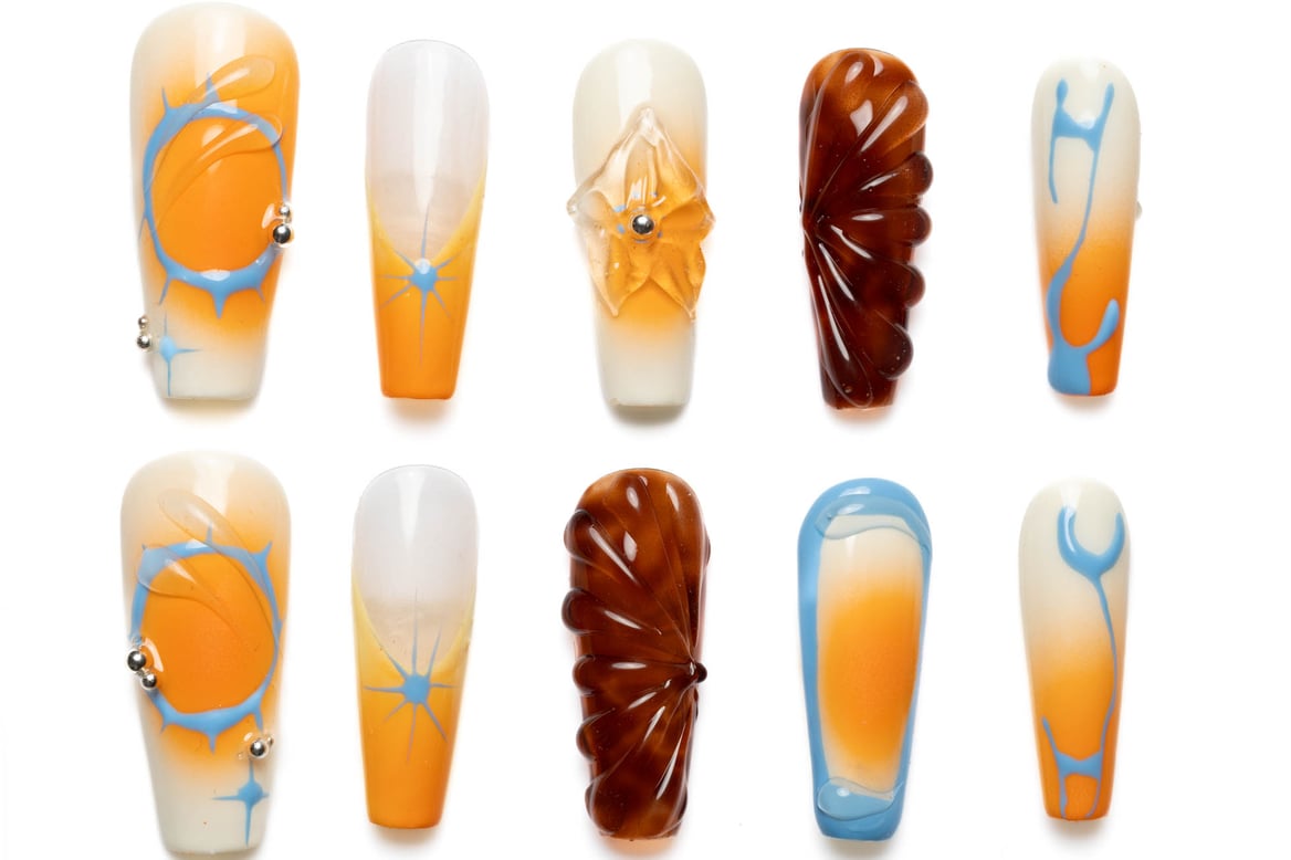 Long coffin press-on nails showcasing orange, white, and blue swirl patterns with brown accents and 3D decorative elements on white background