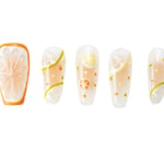 Coffin-shaped press-on nails featuring colorful citrus fruit designs with orange slices, lemons, and limes on a transparent base