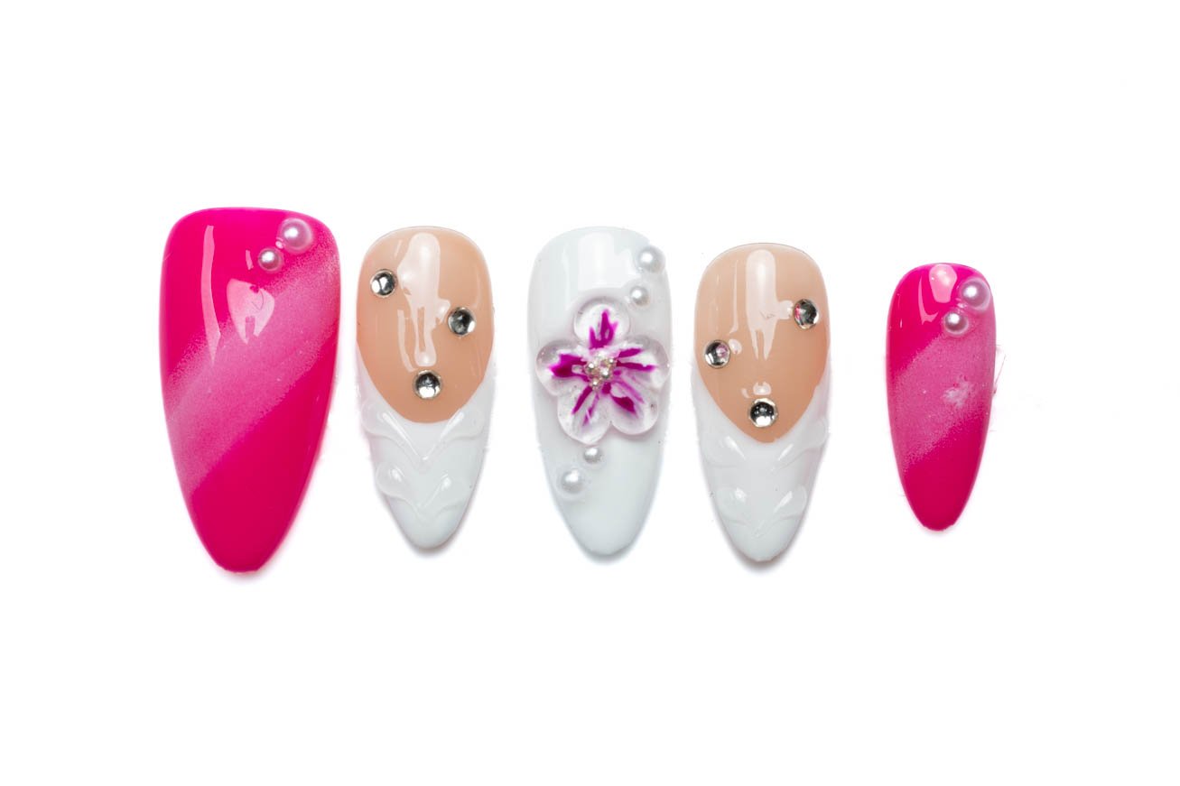 Pink, nude, and white almond-shaped press-on nails with a 3D magenta flower, rhinestones, and pearl accents