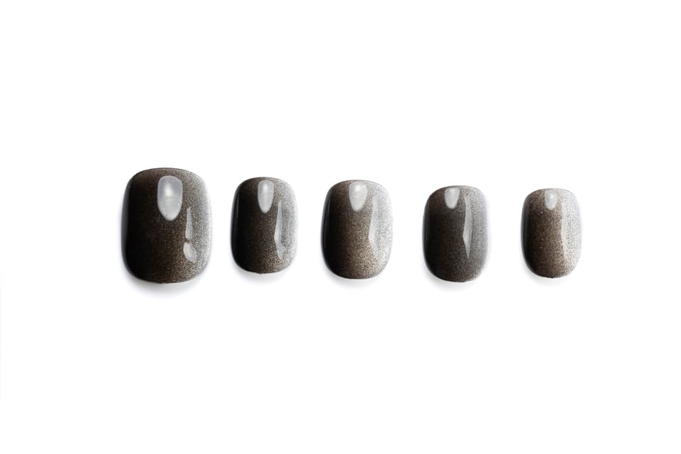 Short squoval press-on nails with dark shimmering cat-eye effect, showing subtle glamour and dimension