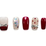 Short coffin press-on nails in burgundy and nude with sparkly rhinestone bow accents, glitter, and polka dot details