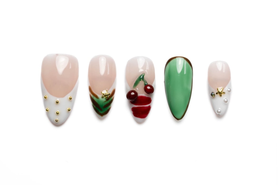 French tip almond press-on nails with cherry designs and pearl accents, medium length with gold star embellishments