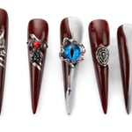 Long stiletto press-on nails in deep red and silver with gothic designs including oni mask, bat, evil eye, and spiderweb embellishments