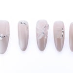 Almond-shaped press-on nails in a sheer nude shade with a 3D butterfly accent and sparkling rhinestones, creating a delicate and whimsical look.