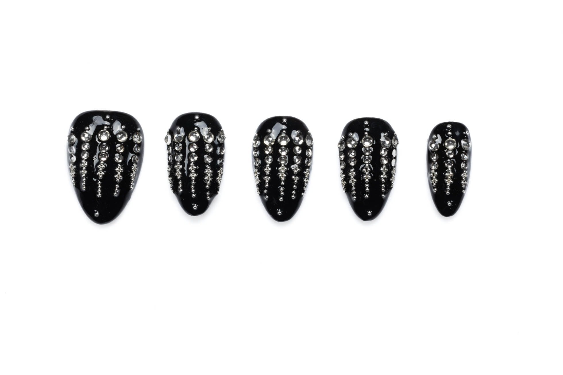 Set of five glossy black almond-shaped press-on nails decorated with vertical cascading rhinestone patterns on white background